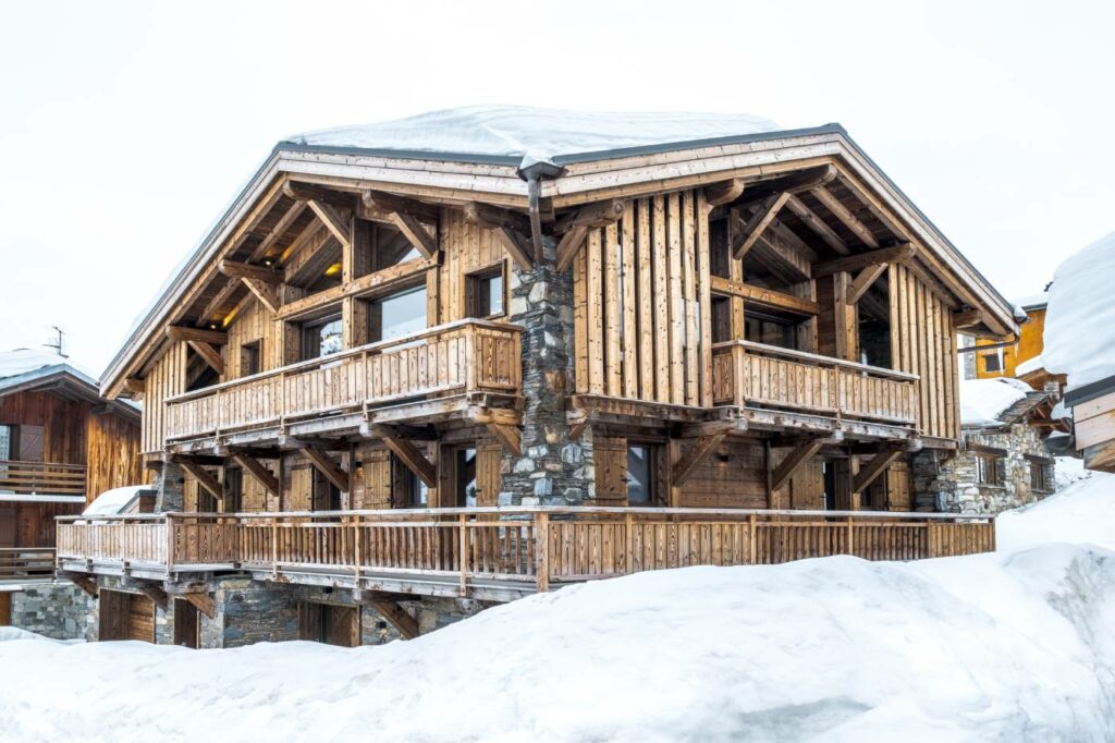 Imposant chalet en bois et pierres naturelles, vue de côté, belle charpente apparente, typique de l'architecture alpine.