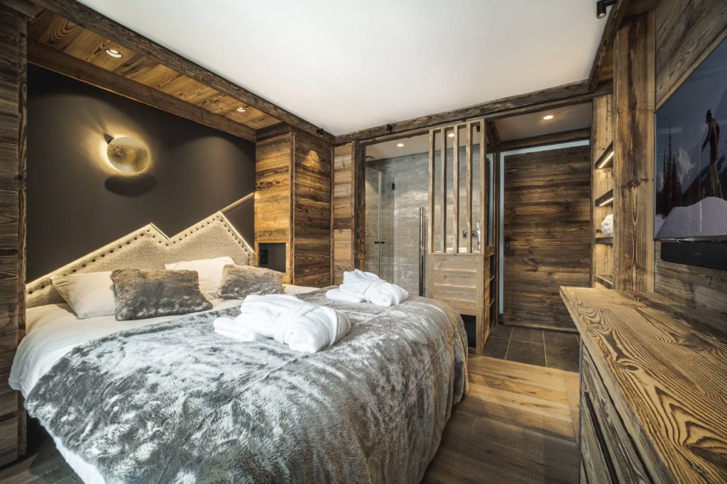 Chambre master avec tête de lit sur mesure, réalisée en cuir et tissu, design de montagne. Chalet bois contemporain.