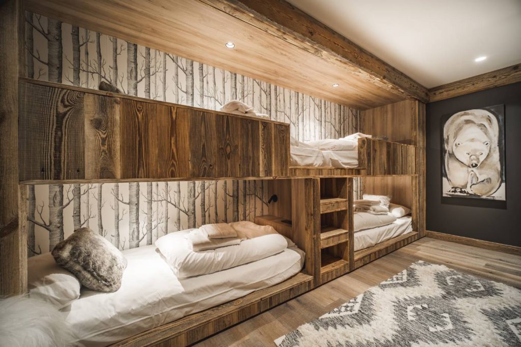 Grande chambre enfant, décor doux en bois et papier peint nature. Lits superposés agencés sur mesure pour permettre un usage dortoir.