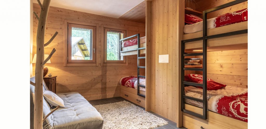 Chambre d'enfant façon dortoir avec des lits superposés en bois, dans un chalet bois sur mesure. Décoration naturelle , en bois, style montagne.